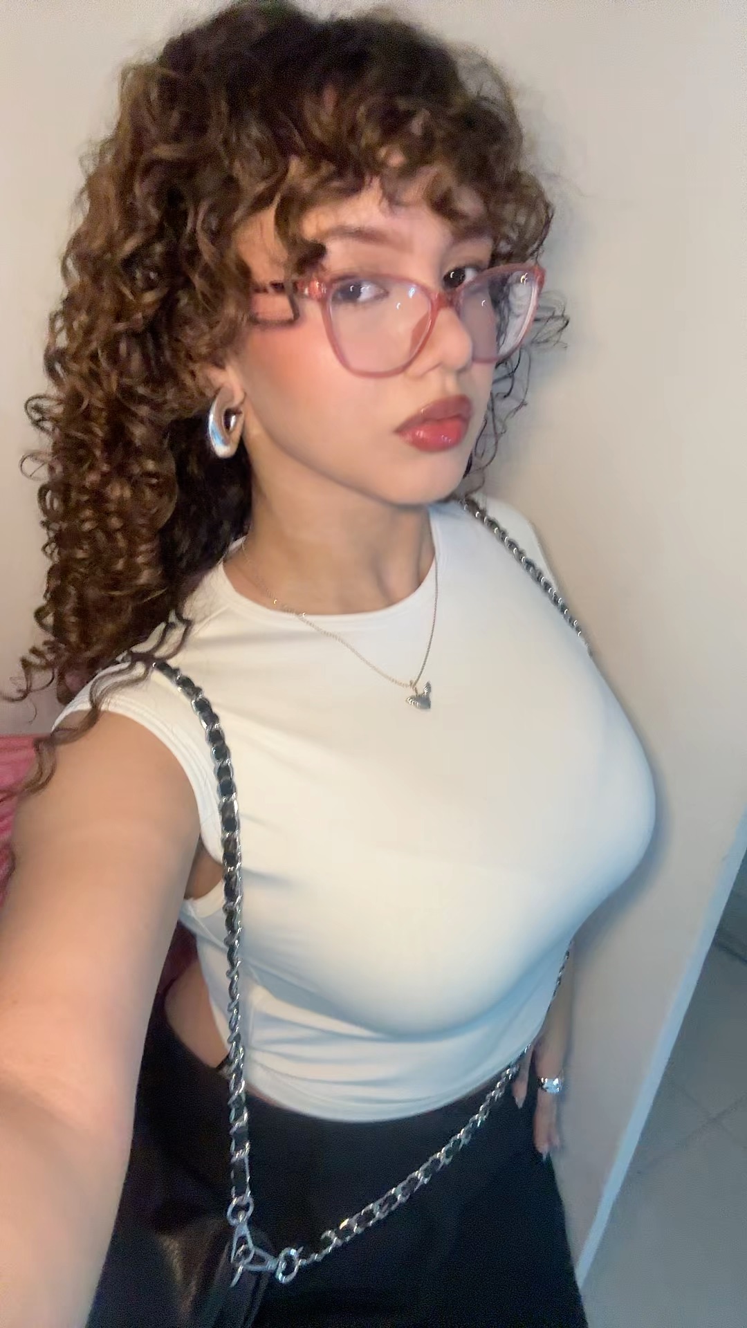 Sarah with curly hair and glasses smiling on a video chat profile
